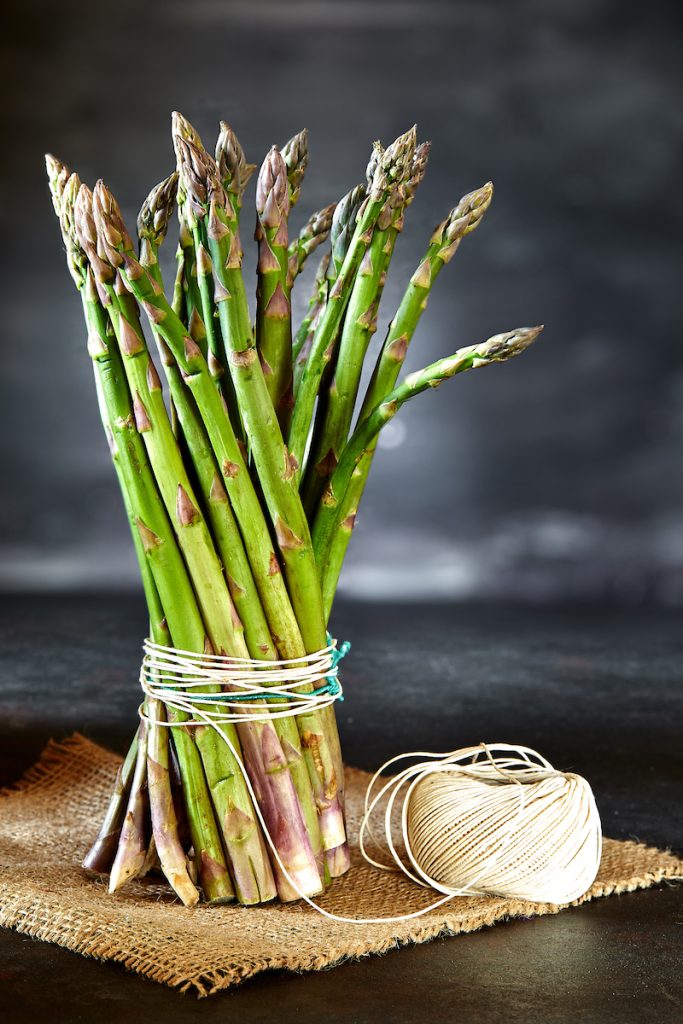 Mazzo di asparagi legati con spago su juta.