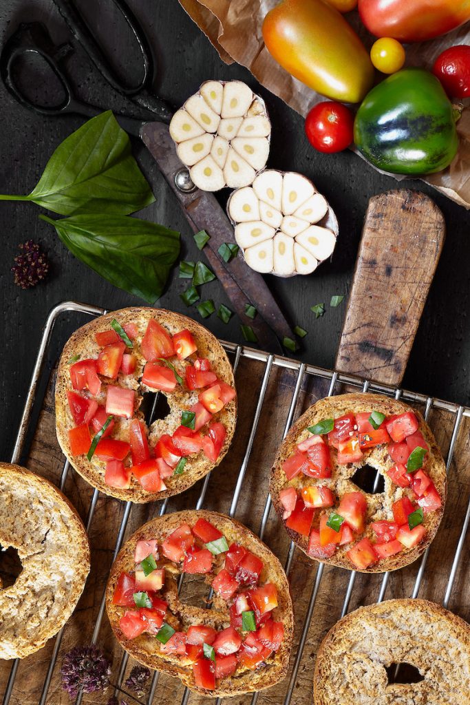 Friselle con pomodoro, aglio e basilico su sfondo scuro.