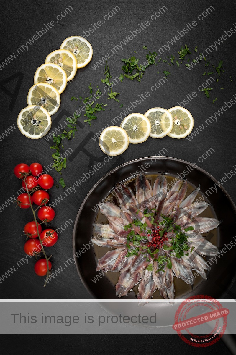 Marinated anchovies with lemon, cherry tomatoes and parsley on a dark background.