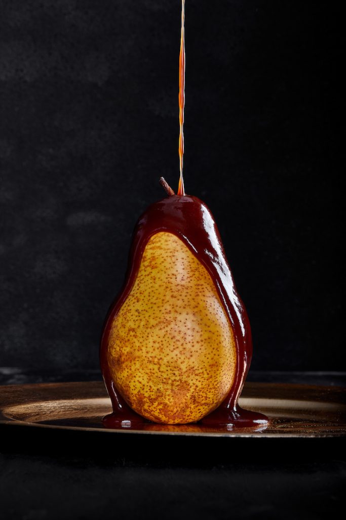 Pera fresca con cioccolato fuso colante su sfondo scuro